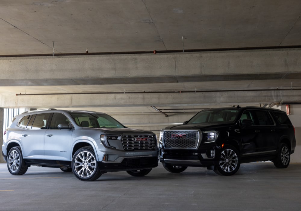 Two GMC SUVs parked facing each other inside of a parking garage