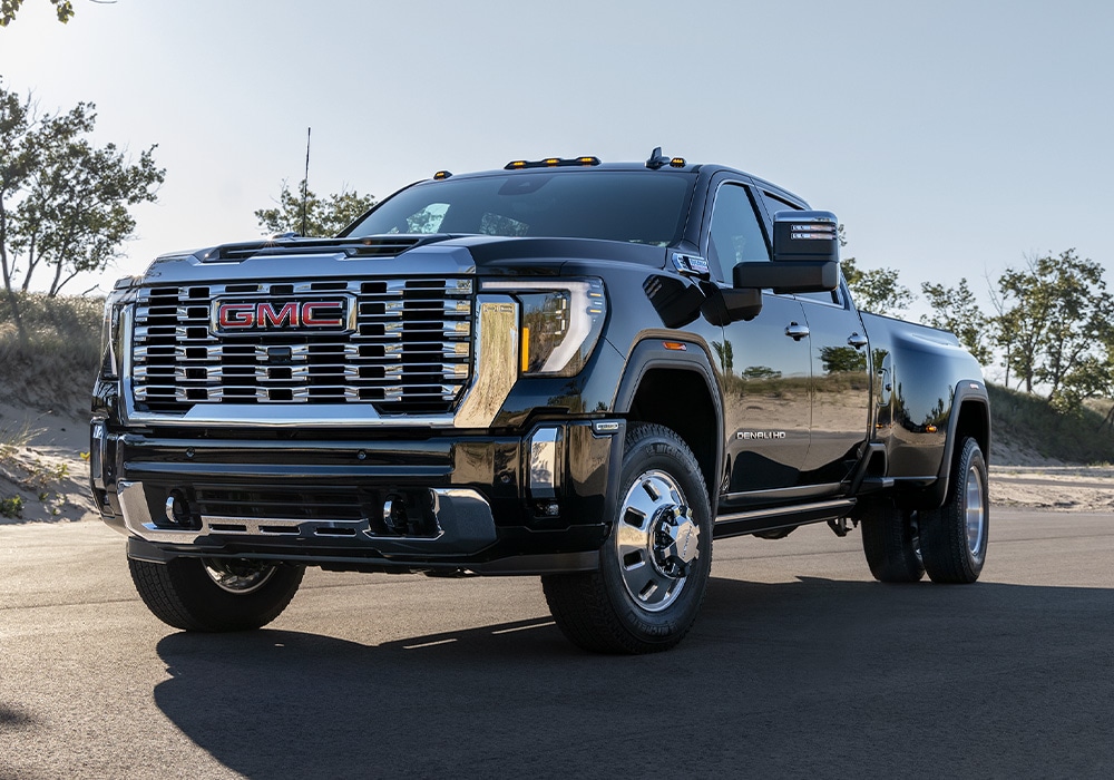 2025-gmc-sierra-greensboro.jpg 3/4 view of the 2025 GMC Sierra 3500 for sale. The truck is black and parked on a paved surface with trees in the background
