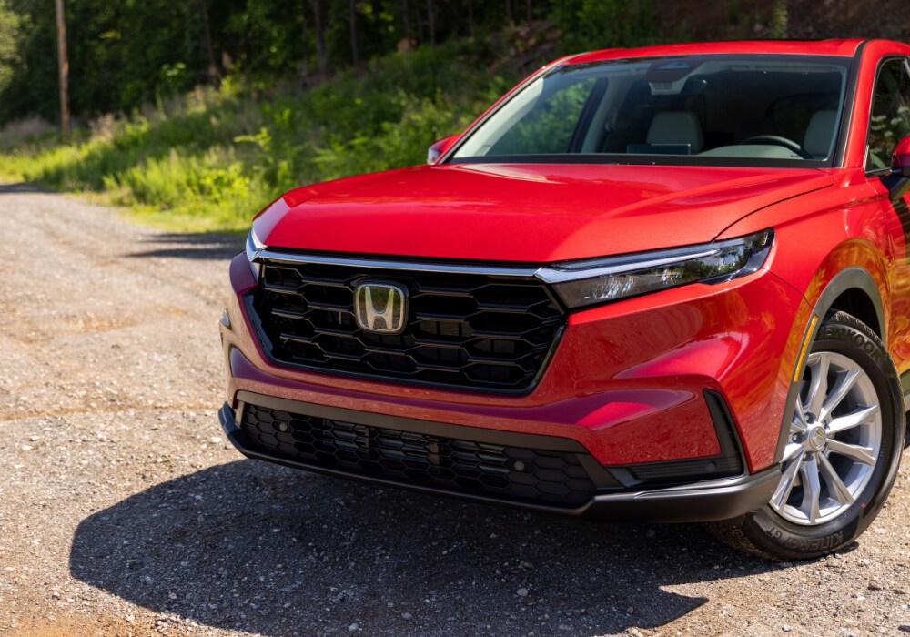 Red 2025 Honda CR-V parked on a gravel road. Photo shows the front half of the car