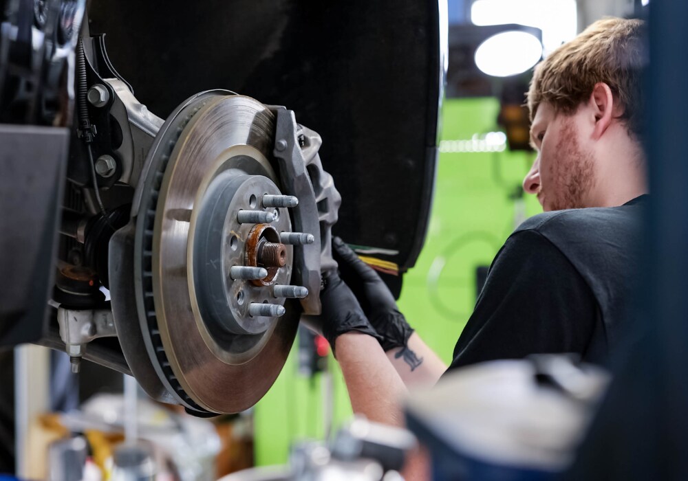 A service technician working on the brakes of a car inside of an automotive service center