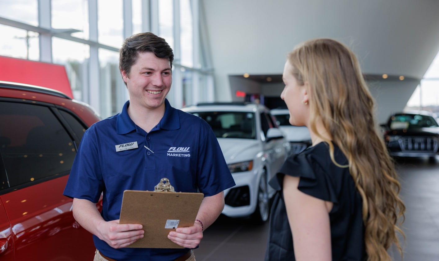 Flow employee holding a clipboard and facing a customer inside a dealership showroom