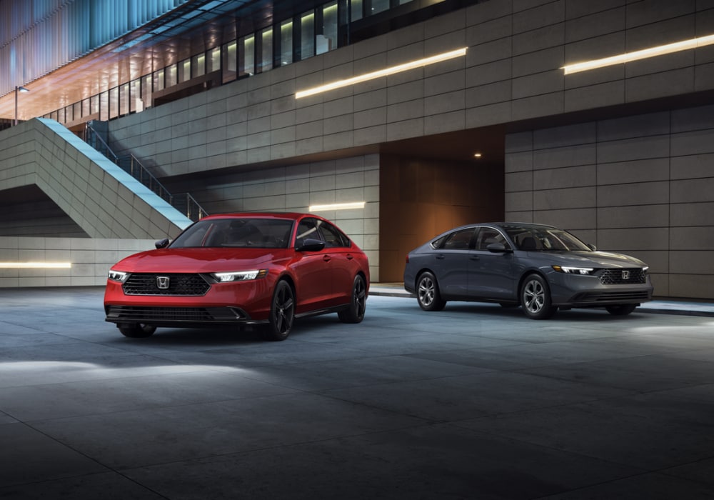 Two Honda Accord Hybrids parked in front of an industrial setting