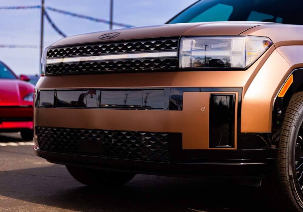 Close up of the front grille of an orange 2026 Hyundai Santa Fe Hybrid SUV