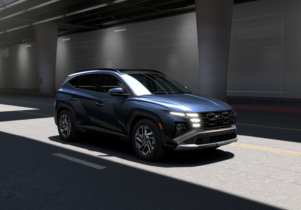 Blue Hyundai Tucson driving down a road with its headlights on