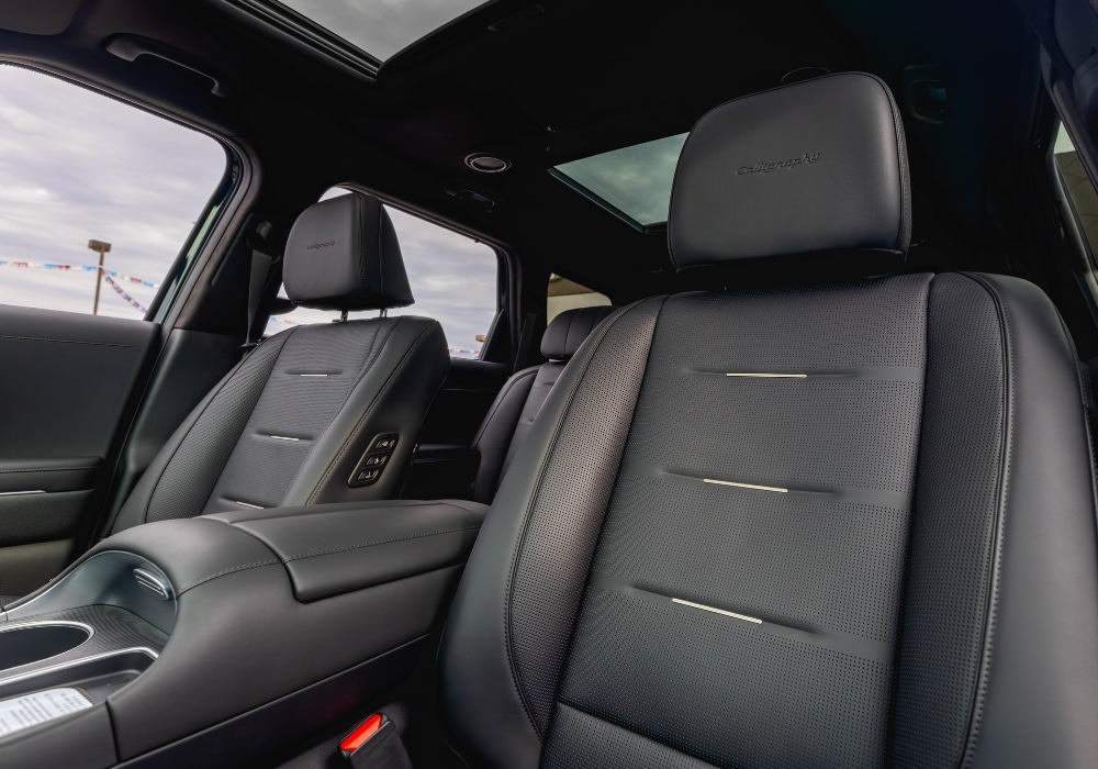 a view of the interior of a 2026 Hyundai Palisade hybrid. the interior is black leather with heated seats and a moonroof