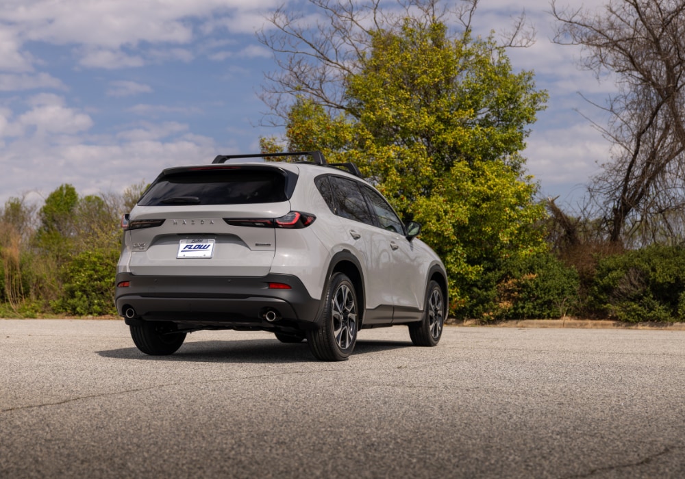 Rear exterior view of the new Mazda Cx-5 parked in an empty lot. There is a Flow Automotive vanity plate attached to the back of the car