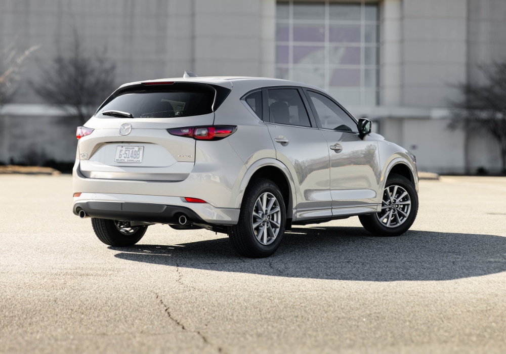 Rear three quarters photo of a new Mazda CX-5 parked in front of a large building