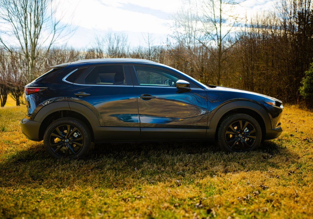 Passenger side view of the 2025 Mazda Cx-30 in a field with trees in the background