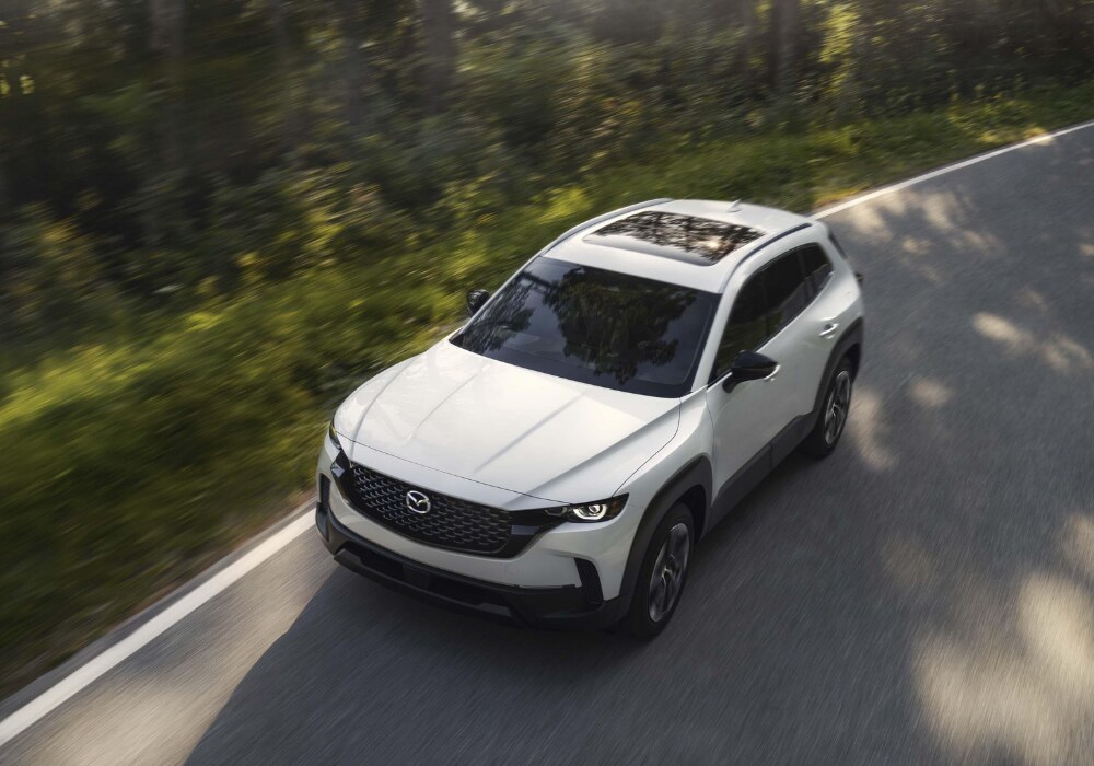2026 Mazda CX-50 Hybrid driving down the road. The SUV is white and the photo shows it from above