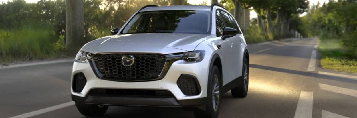 Silver Mazda SUV driving down an empty road