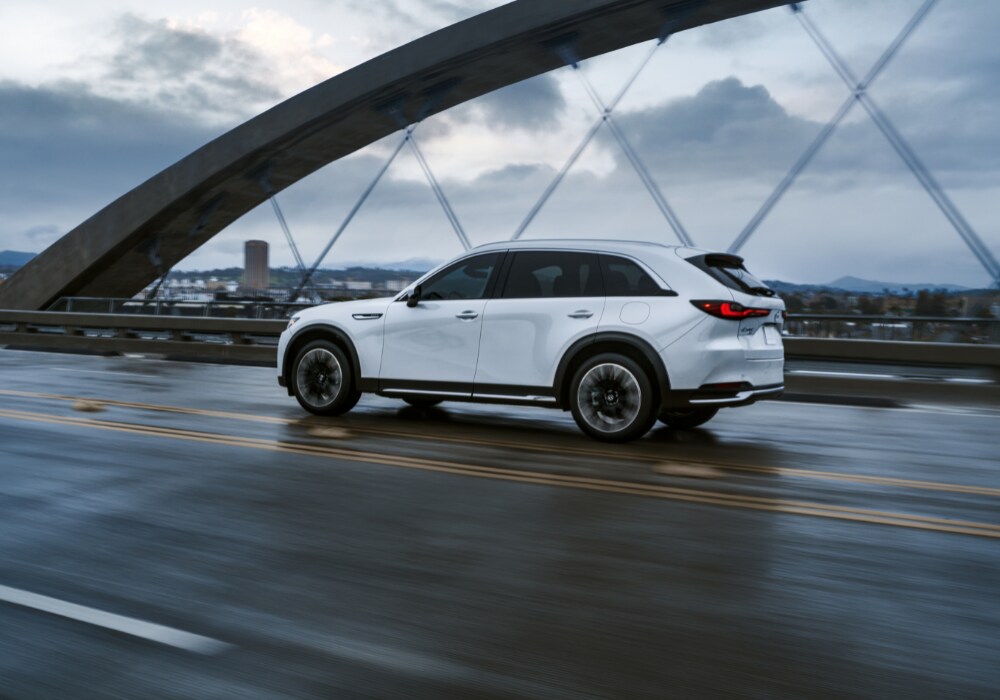 mazda-cx-90-plug-in-hybrid-for-sale.png New MAzda CX-90 driving over a bridge