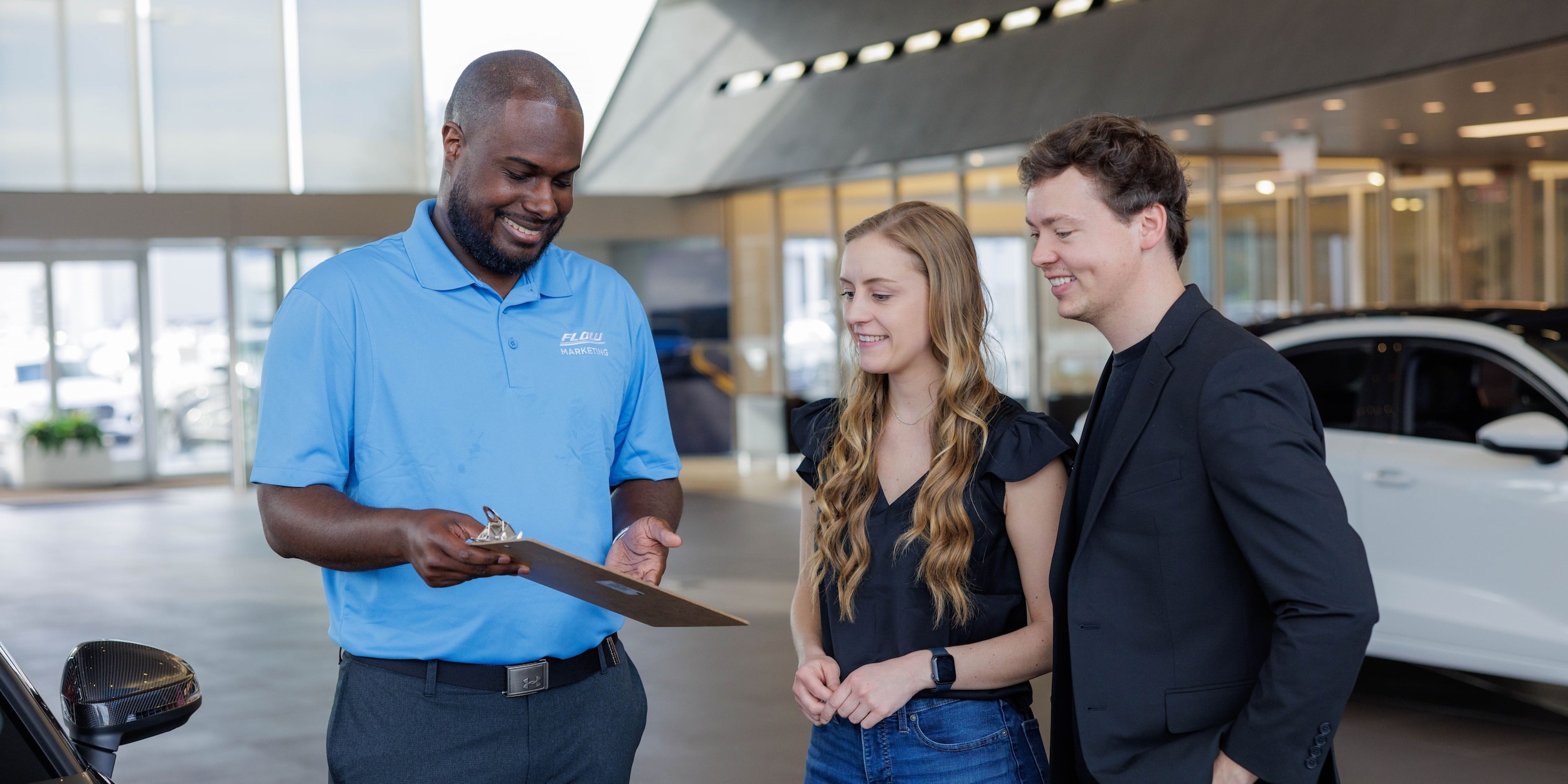 flow-sales.jpg a salesperson reviewing an offer with customers at Flow Mazda in Greensboro, NC.