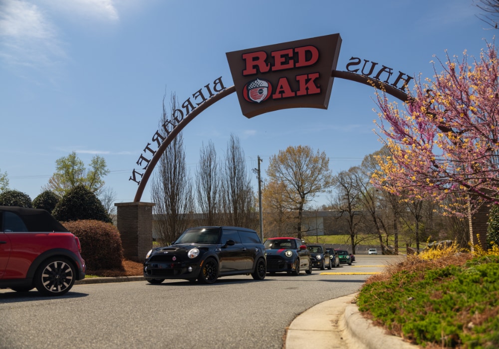 Line up of Mini Cooper car driving underneath the Red Oak Brewery archway