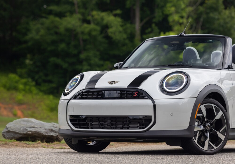 The front of a 2026 Mini Cooper Convertigble. The car is white with black details and the convertible top is down