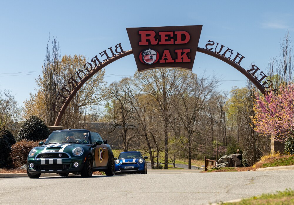 Two Mini Cooper cars driving underneath the Red Oak Brewery arch way