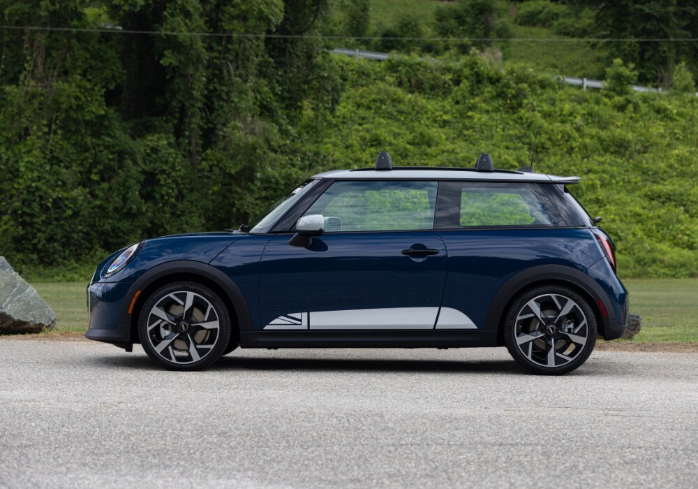 Driver's side view of a new Mini 2 Door for sale. There are trees in the background