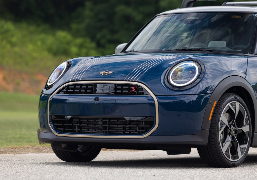 Front half of a 2026 Mini Cooper 2 door car. The car is dark blue with white details