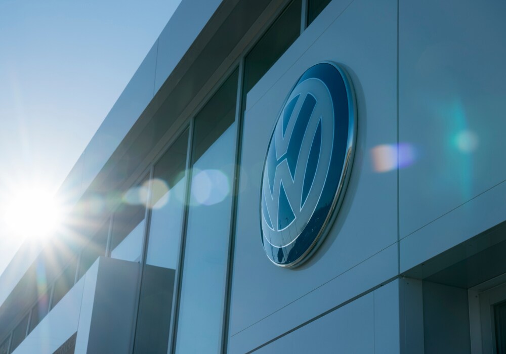 Close up photo of the VW logo on the exterior of the Flow Volkswagen of Greensboro dealership storefront