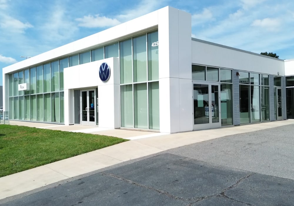 Storefront of the Flow Volkswagen of Winston-Salem dealership. The VW logo is above the front doors