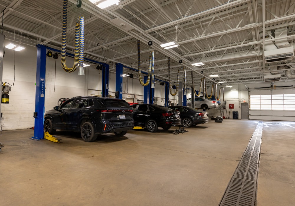 Several Volkswagen cars being worked on inside the Flow Volkswagen of Winston-Salem dealership service department