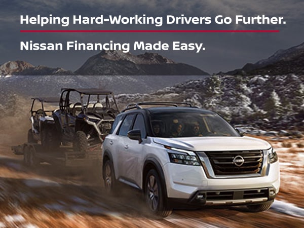 An image of a white Nissan SVU pulling a trailer with mountains in the background. There is a text overlay that reads Helping Hard-Working Drivers Go Further. Nissan Financing Made Easy