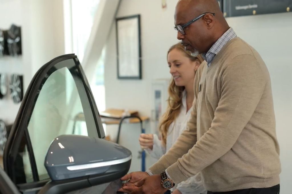 Flow Automotive associate helping customer into car for a test drive