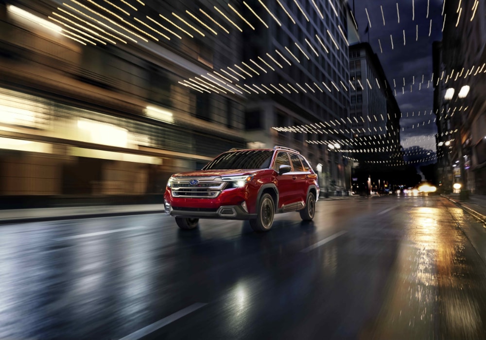 Red 2026 Subaru Ascent driving down a street. The background is blurred
