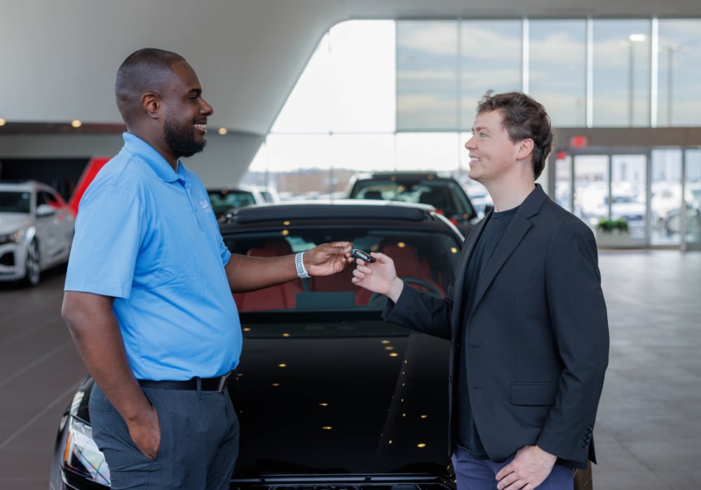 A Flow employee passing a car key to a customer inside of a Flow dealership