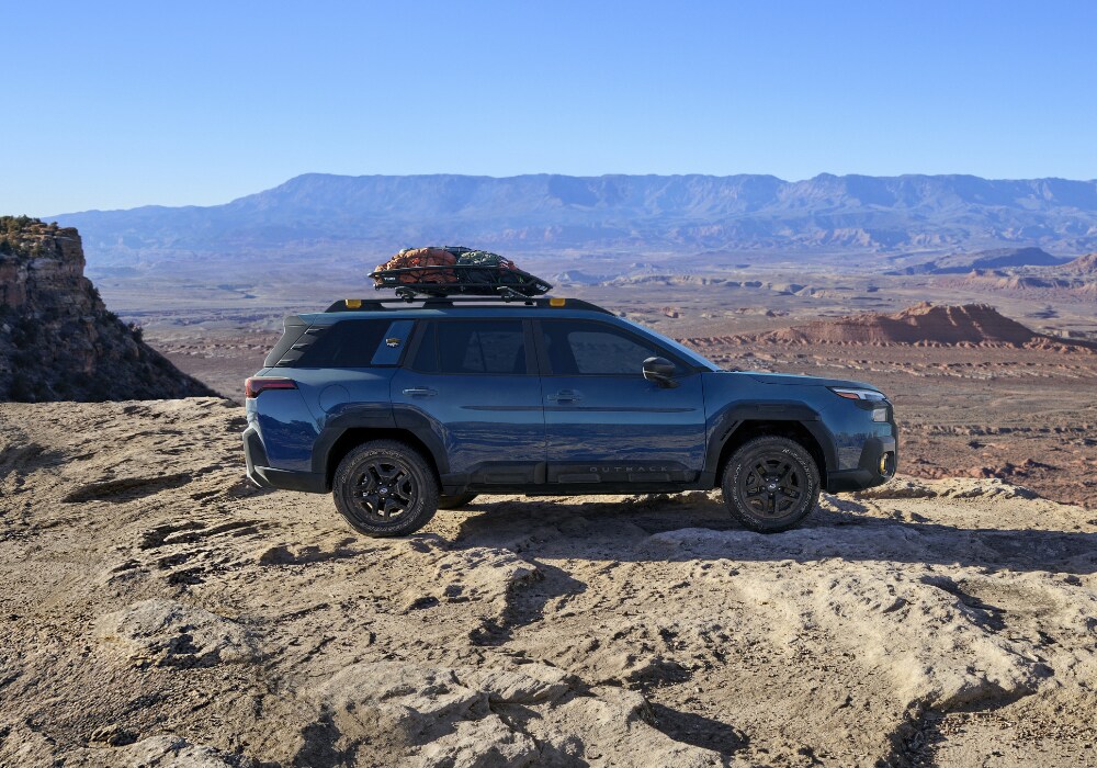 Passenger's side exterior view of a 2026 Subaru Outback Wilderness parked with large mountains in the background