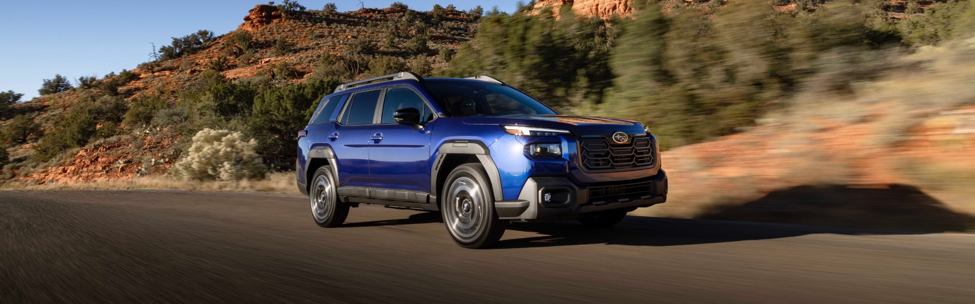 Blue Subaru SUV driving down a road