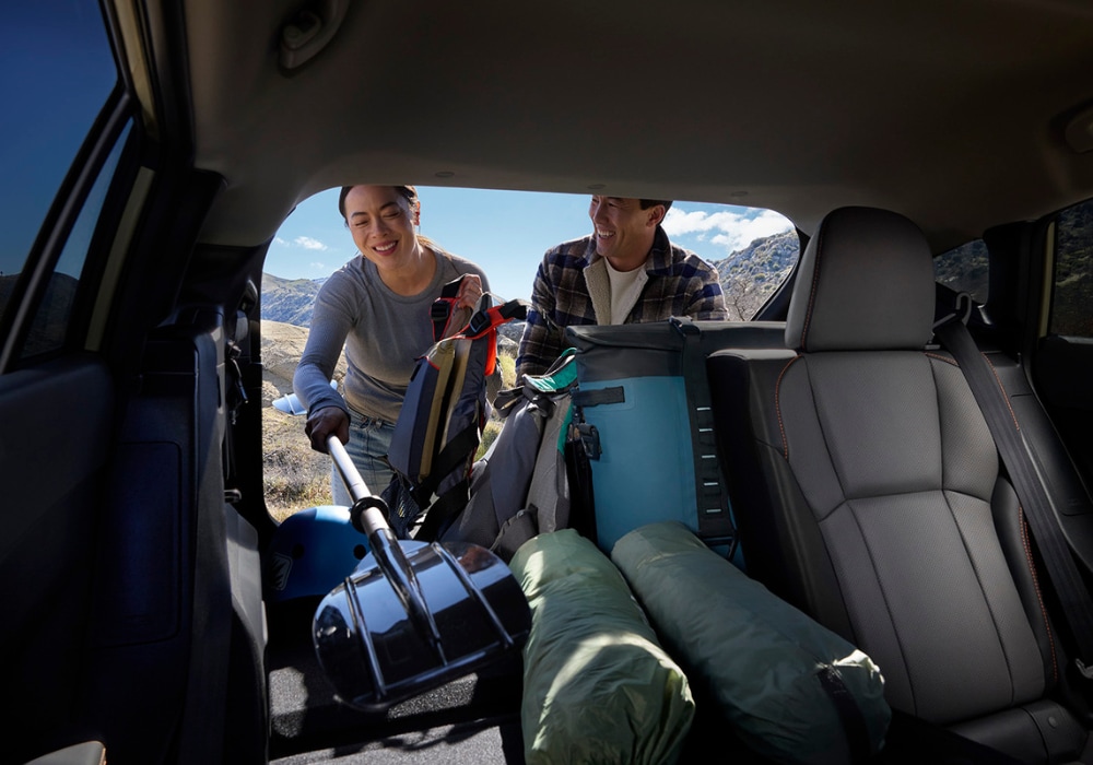 Two people loading their gear into the trunk of a Subaru Crosstrek Hybrid