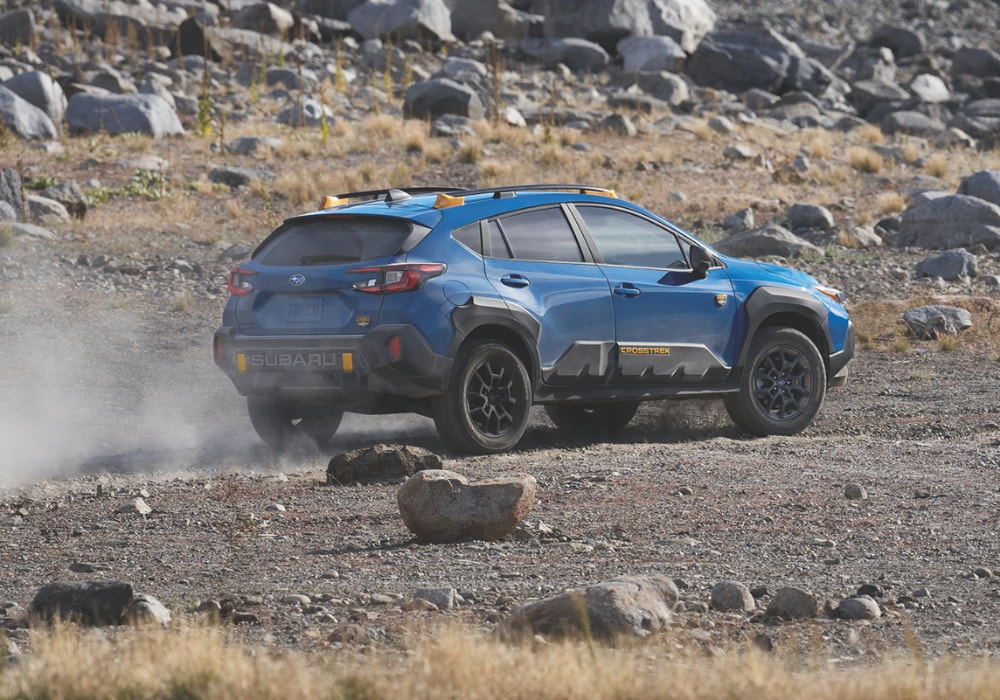 Rear 3/4 passenger side view of a 2026 Subaru Crosstrek Wilderness in a rocky terrain