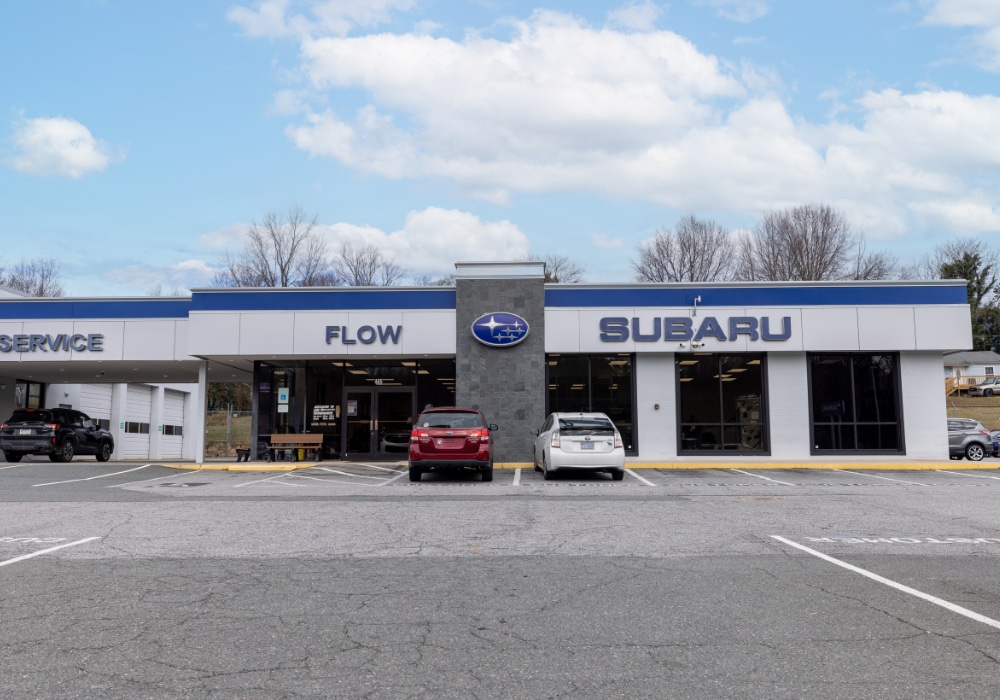 Flow Subaru dealership with several cars parked outside. The sky in the background is blue