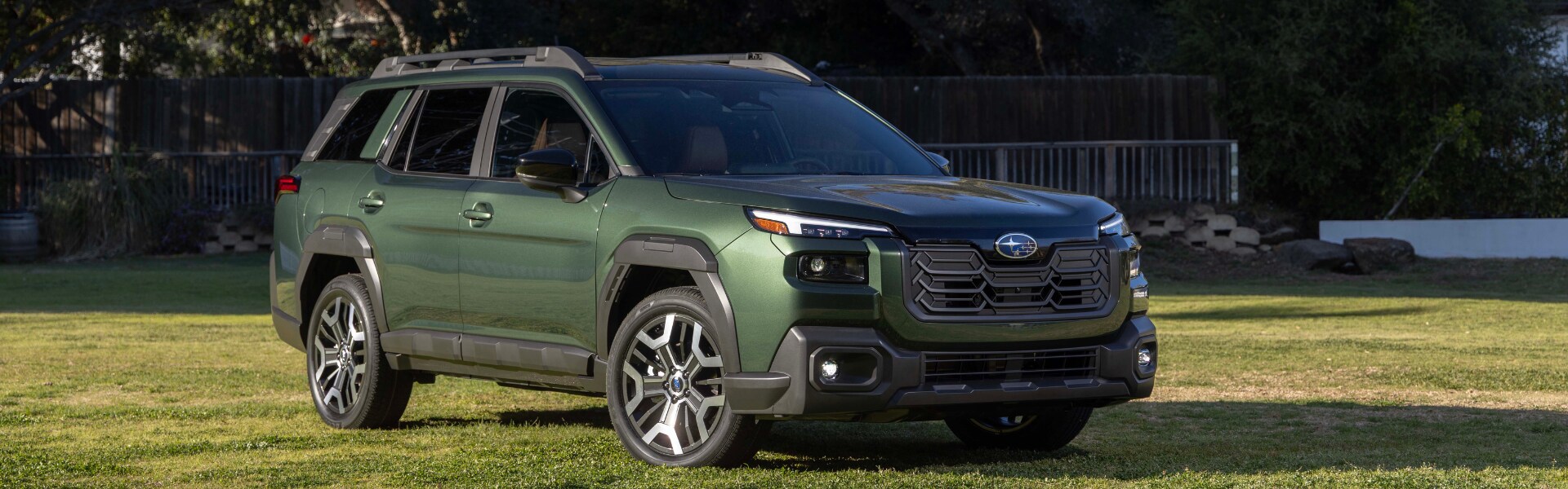 Green Subaru Outback parked on a field of grass