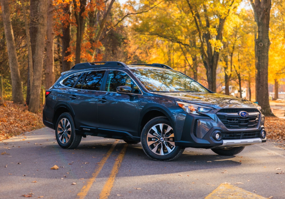 Gray 2024 Subaru Outback parked on a road with trees behind the vehicle. The trees have yellow and oranges leaves
