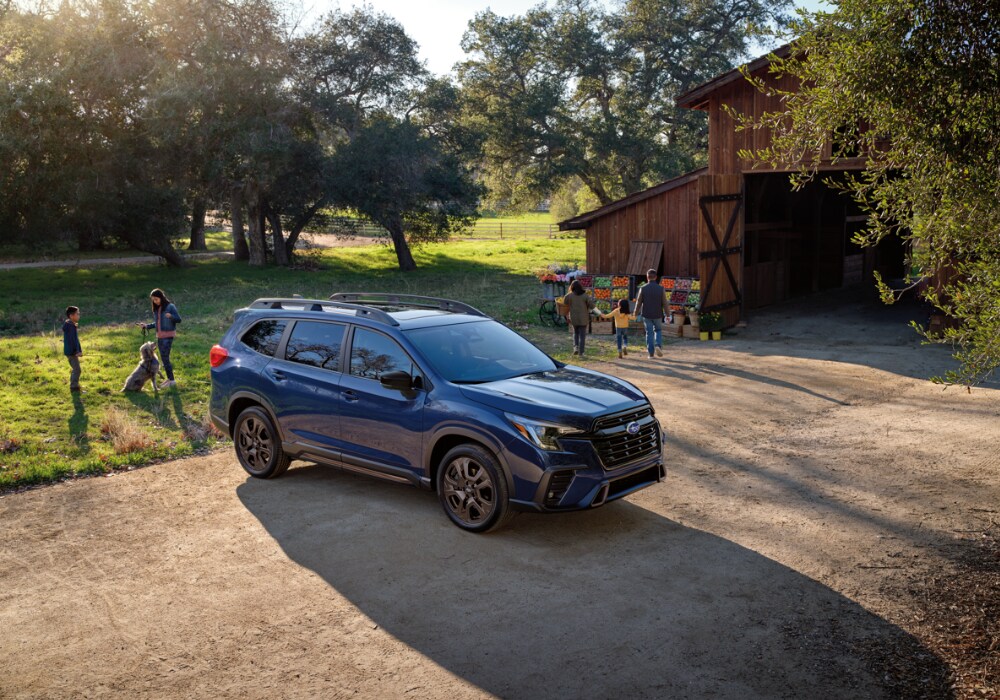 2025 Subaru Ascent parked in front of a barn with people in the background