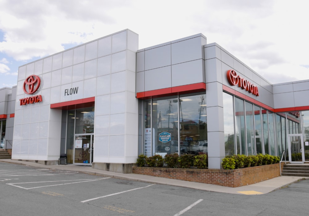 Storefront of the Flow Toyota of Charlotteville dealership with a cloudy sky in the background