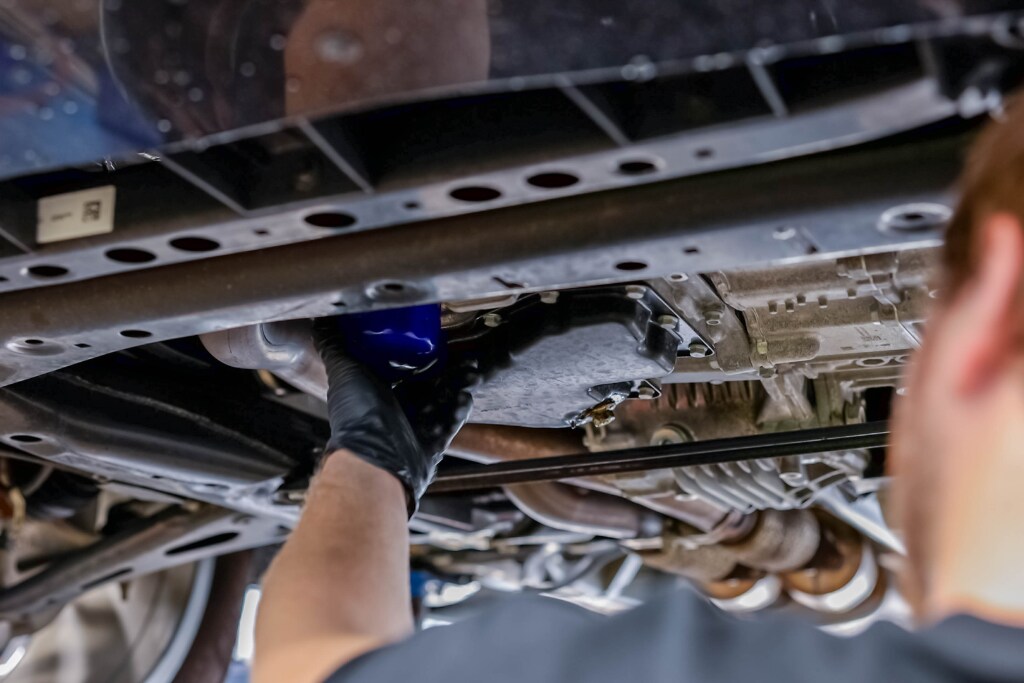 Expert Toyota service near me working underneath a vehicle during an oil change