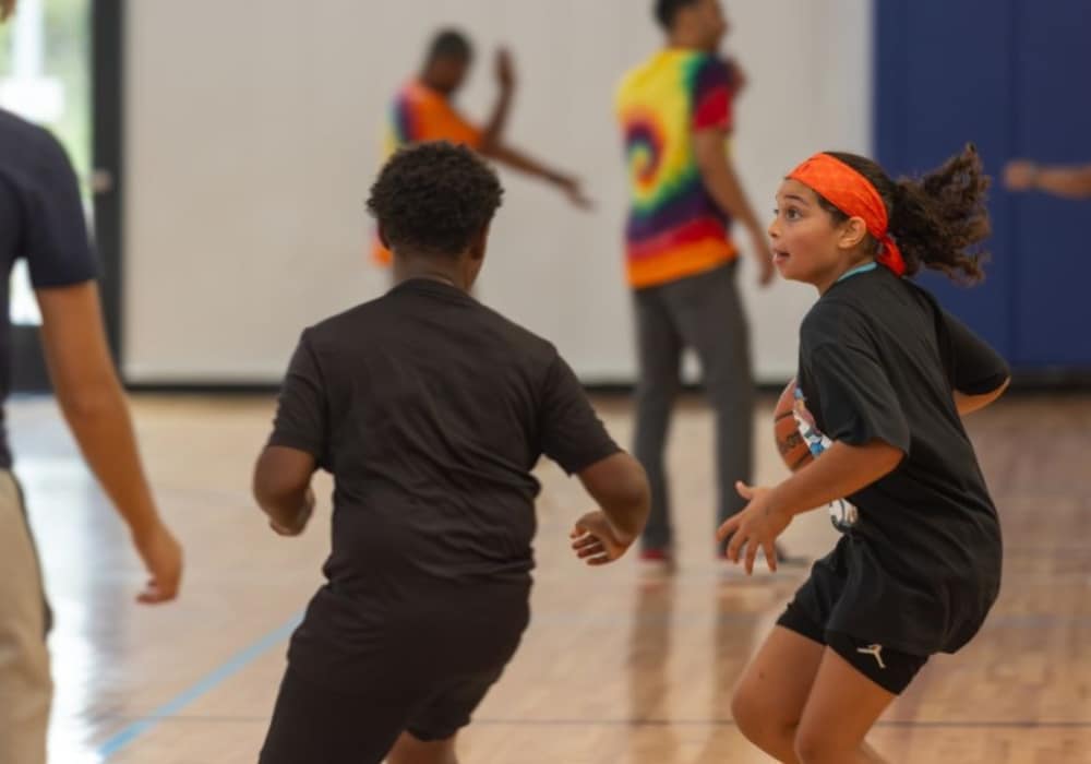 Members of the HER Sports camp playing basketball