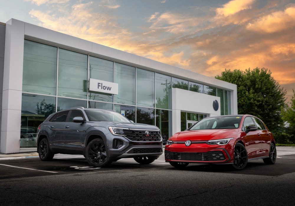 Two Volkswagen cars parked outside the Flow Volkswagen of Asheville dealership storefront