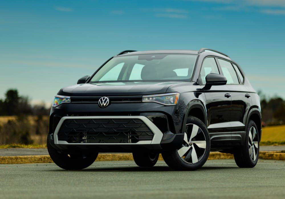 Black 2025 Volkswagen Taos SUV parked with trees and a blue sky in the background