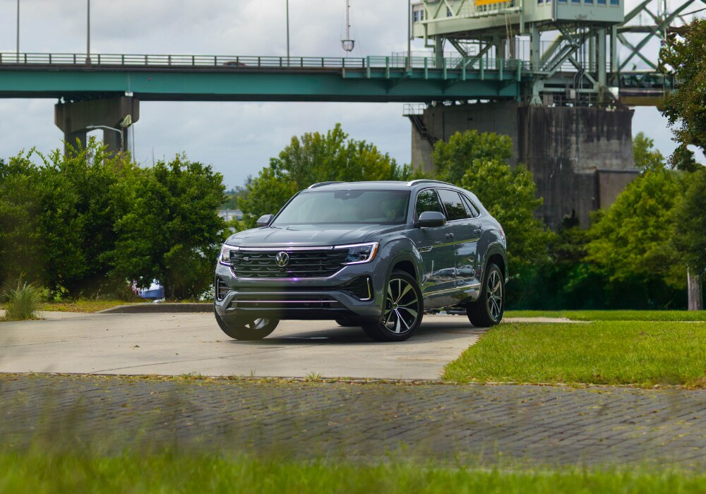 Dark gray Volkswagen Atlas Cross Sport SUV parked in front of a bridge