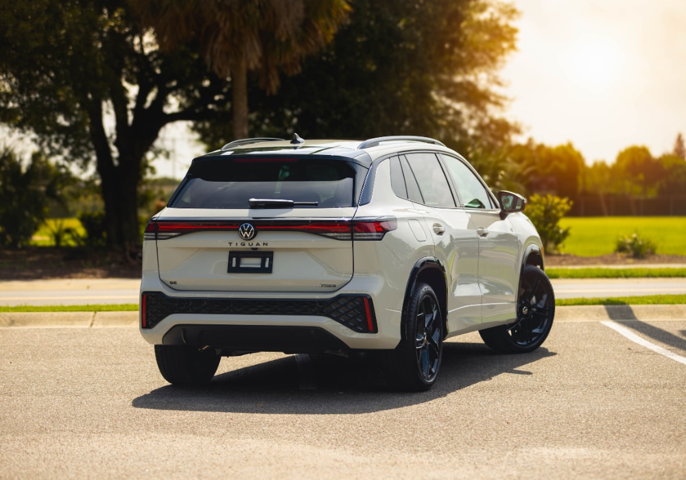 Rear exterior photo of the 2025 VW Tiguan SUV parked on a paved surface with trees in the background