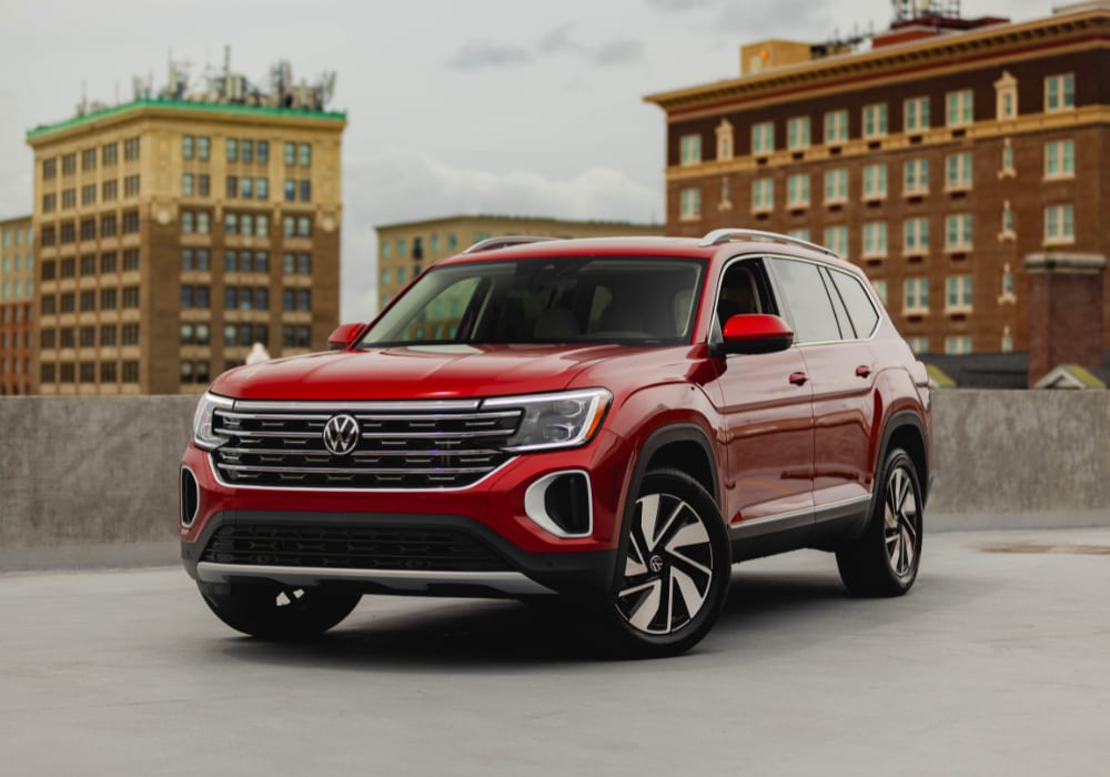 2025-volkswagen-atlas.png Red 2025 Volkswagen Atlas parked in front of tall buildings