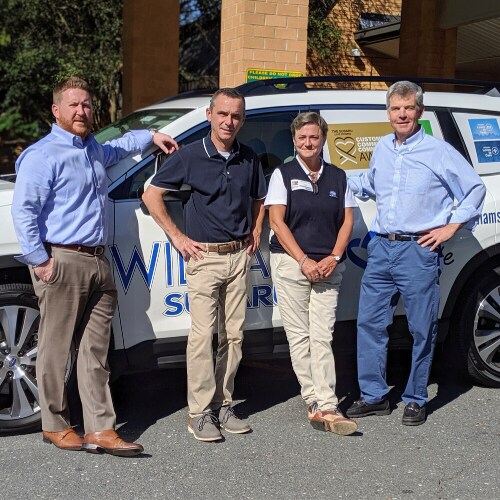 Williams Subaru employees are shown in front of a Williams Subaru vehicle.