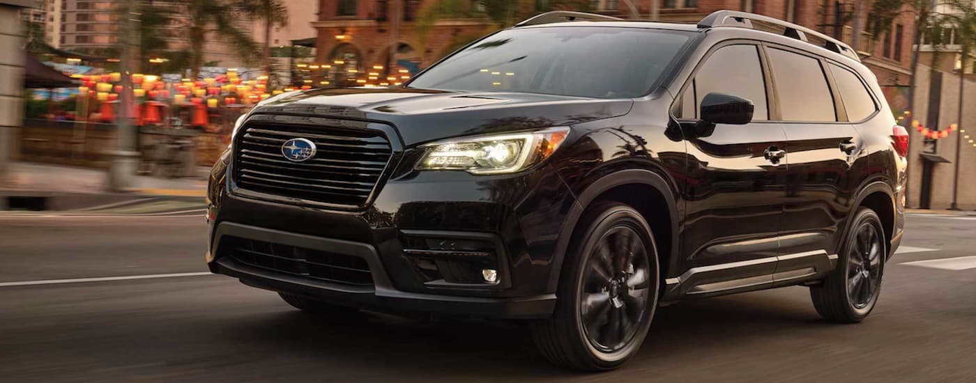 A black 2022 Subaru Ascent Onyx is shown from the side driving through a city.
