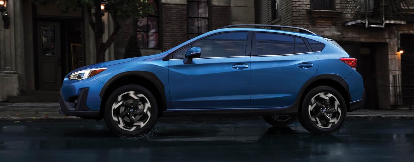 A blue 2022 Subaru Crosstrek Limited is shown from the side driving on a wet road.