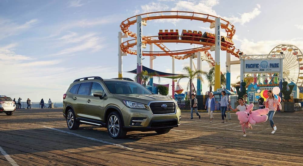 A green 2022 Subaru Ascent Limited is shown parked in front of a carnival.