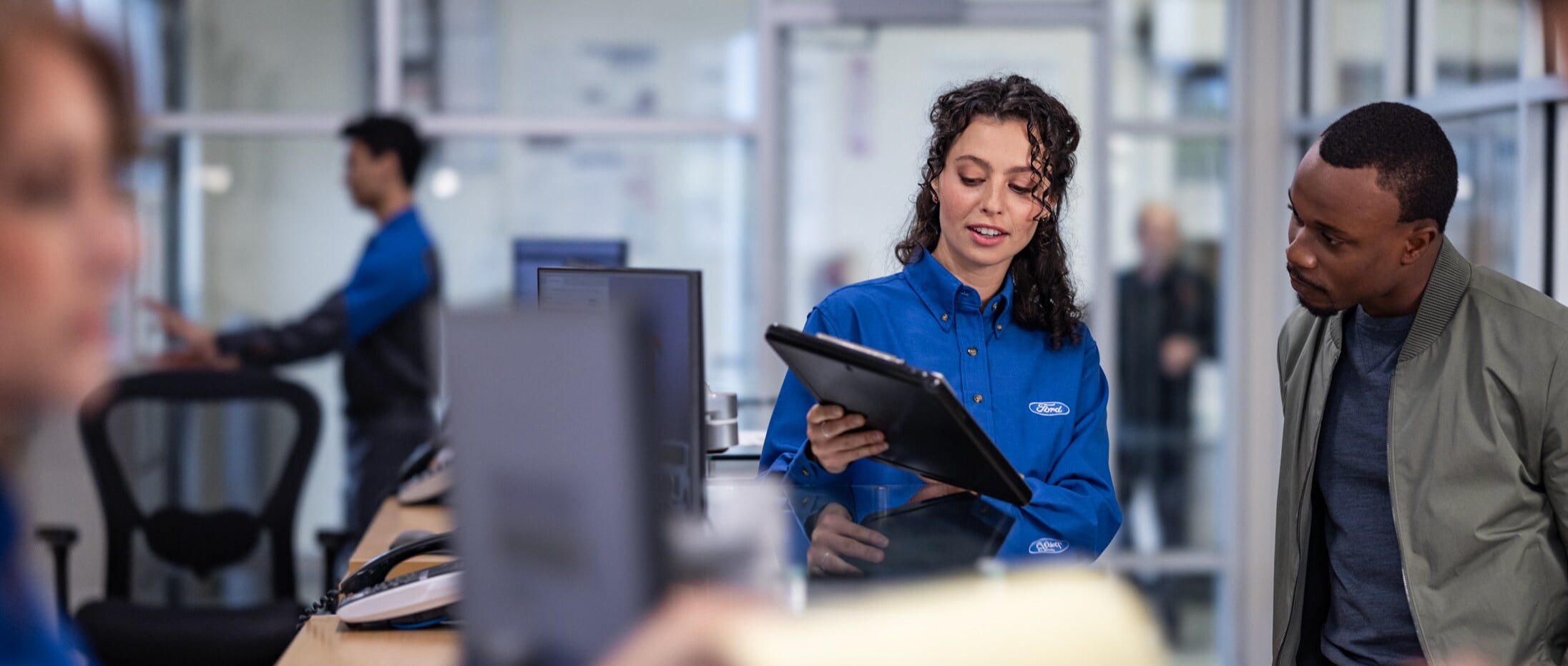 A Ford employee showing a customer information on their tablet.