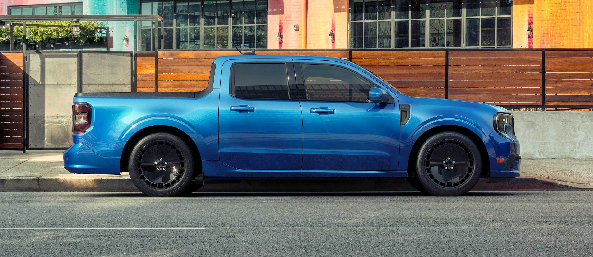 Profile view of a blue Ford Maverick® Lobo™ pickup parked in front of a restaurant patio